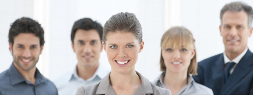 Three smiling professionals in business dress standing together in a bright office