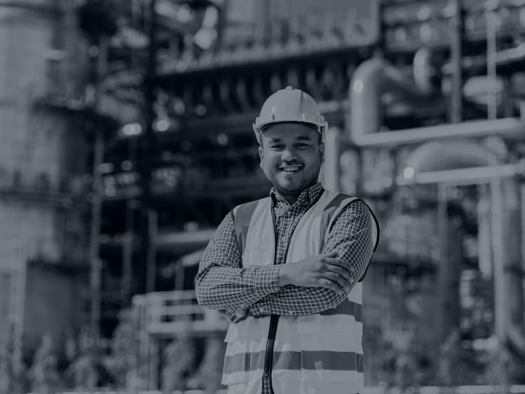 Chemical engineer in a hard hat and hi-vis vest in front of a chemical processing plant