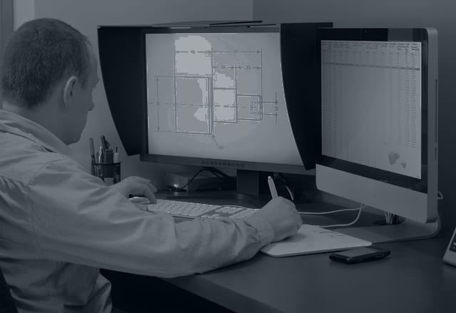 Engineer working on technical drawings at a CAD workstation
