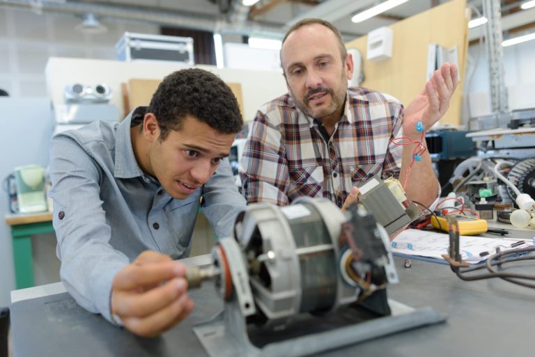 Apprentice engineer learning from an experienced colleague in a workshop