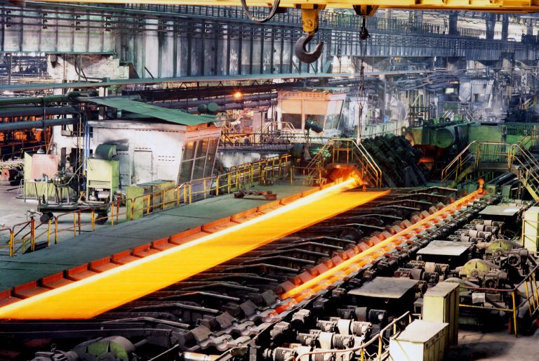 Glowing red-hot steel slab on rollers in a steelworks
