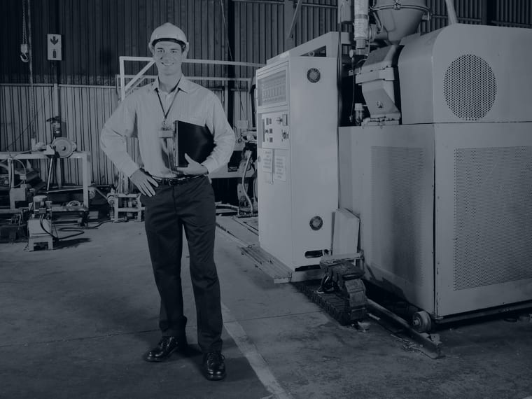 Maintenance manager with a clipboard beside plant machinery
