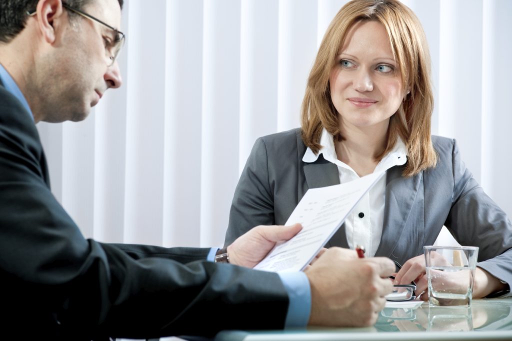Manager and colleague discussing documents across a desk in a meeting