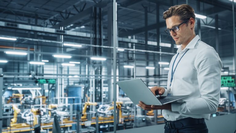 Process engineer monitoring an automated line on a laptop