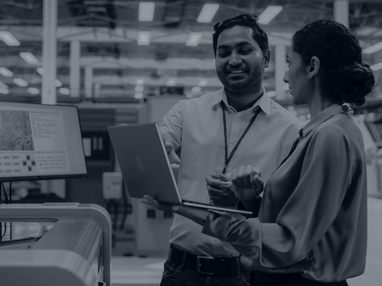 Project engineers reviewing plans on a laptop in a factory