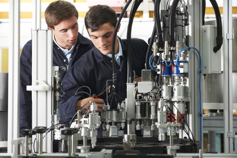 Two engineers inspecting production machinery together on a factory floor